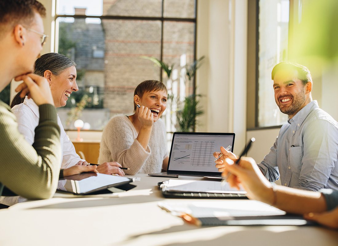 Read Our Reviews - Group of Cheerful Employees Sitting Around a Table During a Business Meeting in a Bright Conference Room in the Office